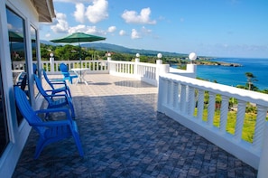 A balcony with blue chairs, a table, and a green umbrella. - Da Villa Juanita  (Hordley)