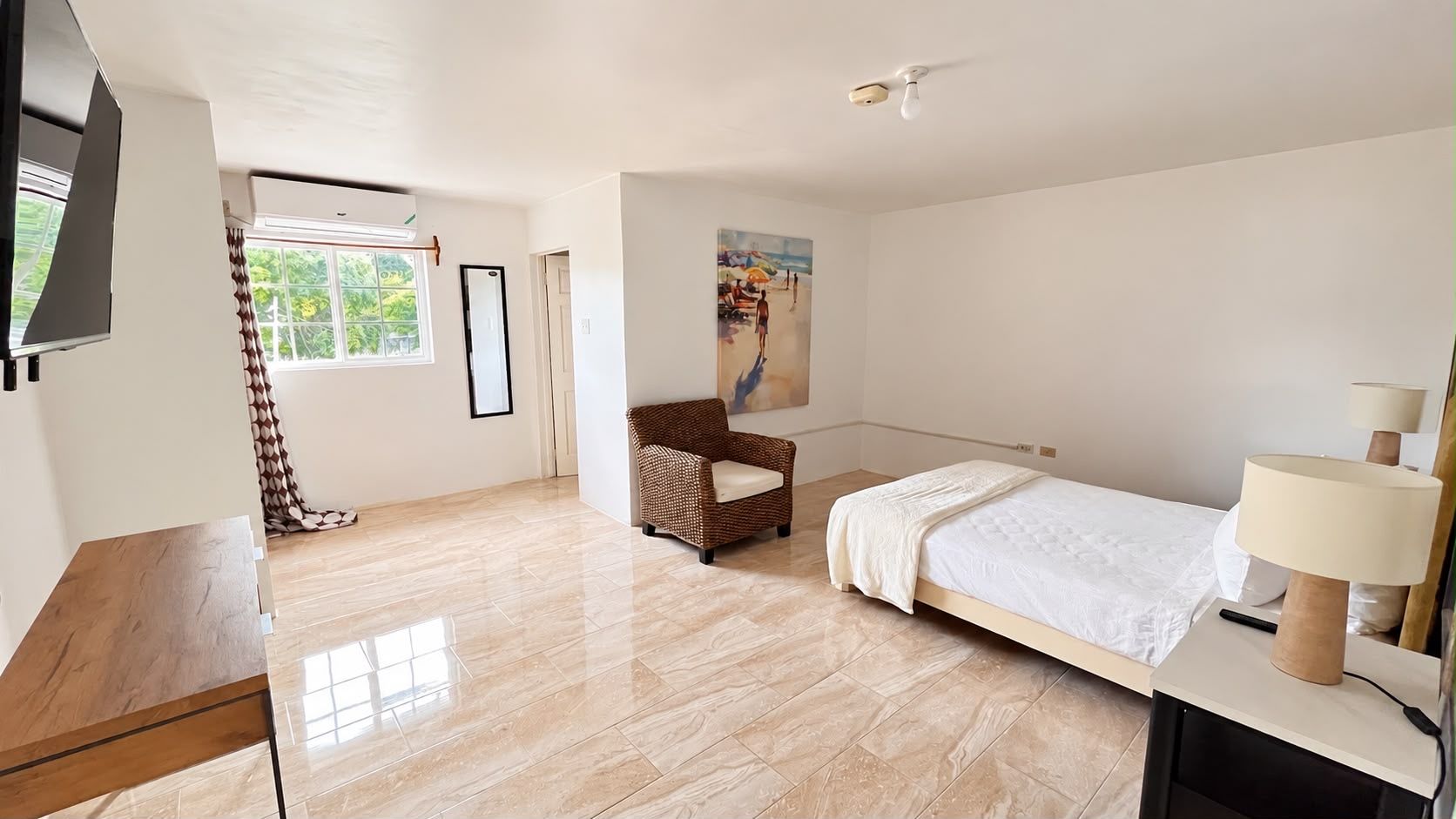A bedroom with a bed, a chair, a desk, a lamp, and a painting on the wall.