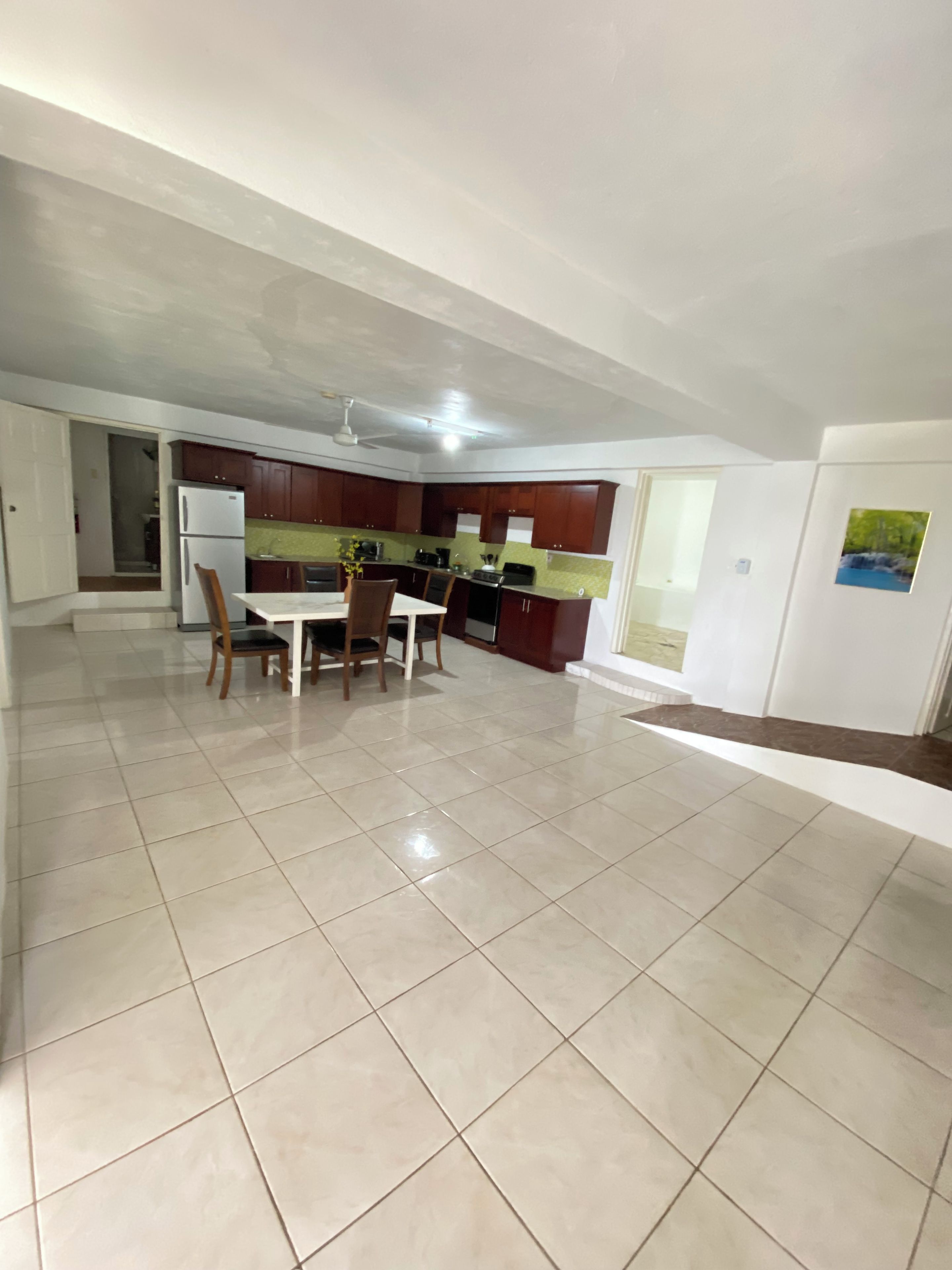 A spacious kitchen with a dining area, a refrigerator, and a ceiling fan.