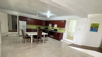 Cozinha espaçosa com área de refeições, geladeira e ventilador de teto.