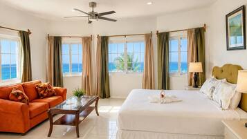 Una habitación de hotel con una cama, un sofá, una mesa de centro y vista al mar.