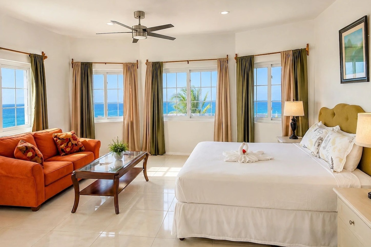 Una habitación de hotel con cama, sofá, mesa de centro y vista al mar.