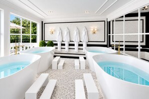 Ein Spa-Raum mit zwei großen Badewannen, einem Handtuchhalter an der Wand und Blick auf die grüne Umgebung.