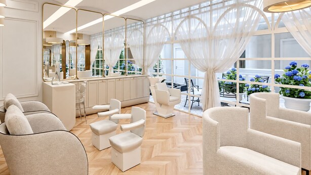 Ein modernes Interieur mit einer zentralen Sitzecke, einer Bar und großen Fenstern mit durchsichtigen Vorhängen.