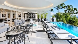 Ein moderner Außenbereich mit Lounge-Möbeln, einem Pool und Blick auf die umliegende Bepflanzung.