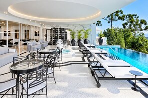 Ein moderner Außenbereich mit Lounge-Möbeln, einem Pool und Blick auf die umliegende Bepflanzung.