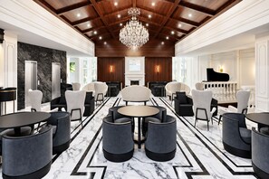 A spacious lobby with marble flooring, a grand chandelier, and a piano.