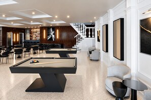 Un área de estar moderna con mesas de billar, asientos y un bar.