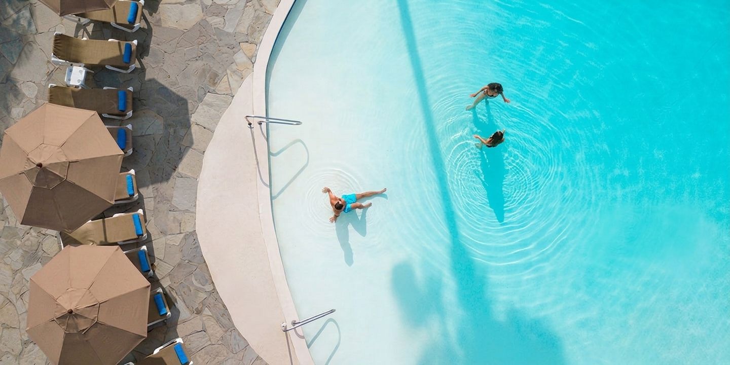 Una piscina con sillones de descanso y sombrillas.
