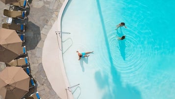 Una piscina con sillones de descanso y sombrillas.