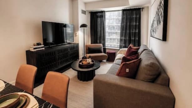 Una sala de estar moderna con un sofá, una mesa de centro, un televisor y un comedor con sillas y una mesa.