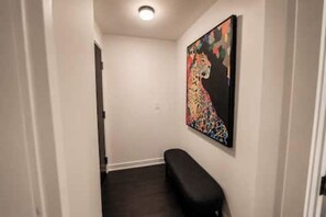 Un pasillo con un banco, una puerta y un cuadro abstracto colorido en la pared.