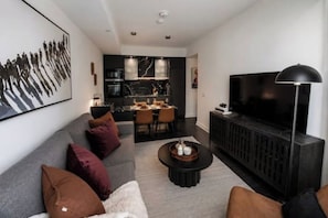 A modern living room with a sofa, coffee table, and a flat-screen TV. - Luxury Yorkville Condo Sleeps 3 (Toronto)