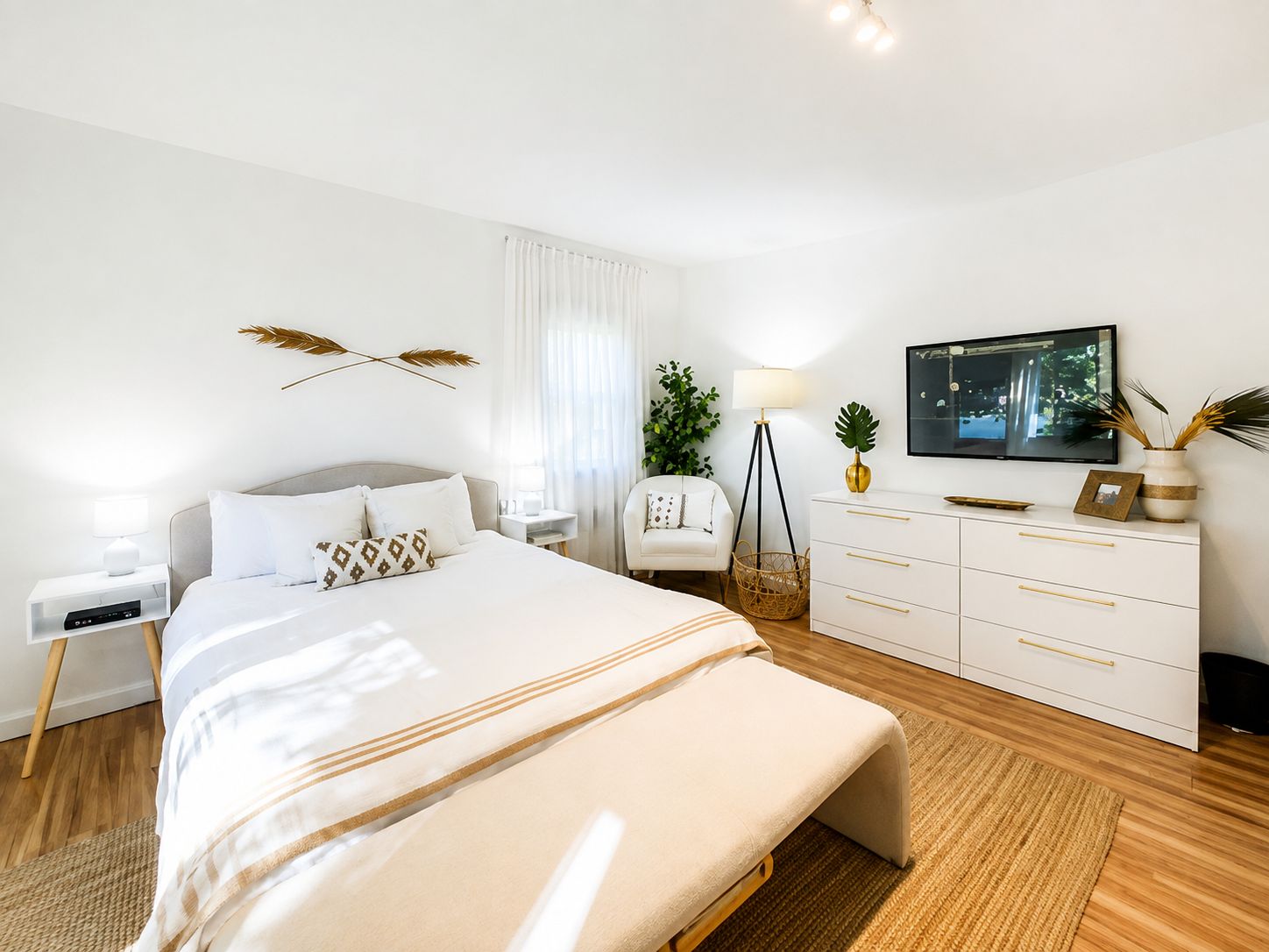 Une chambre à coucher moderne, avec un lit, des tables de chevet, une télévision et une commode.