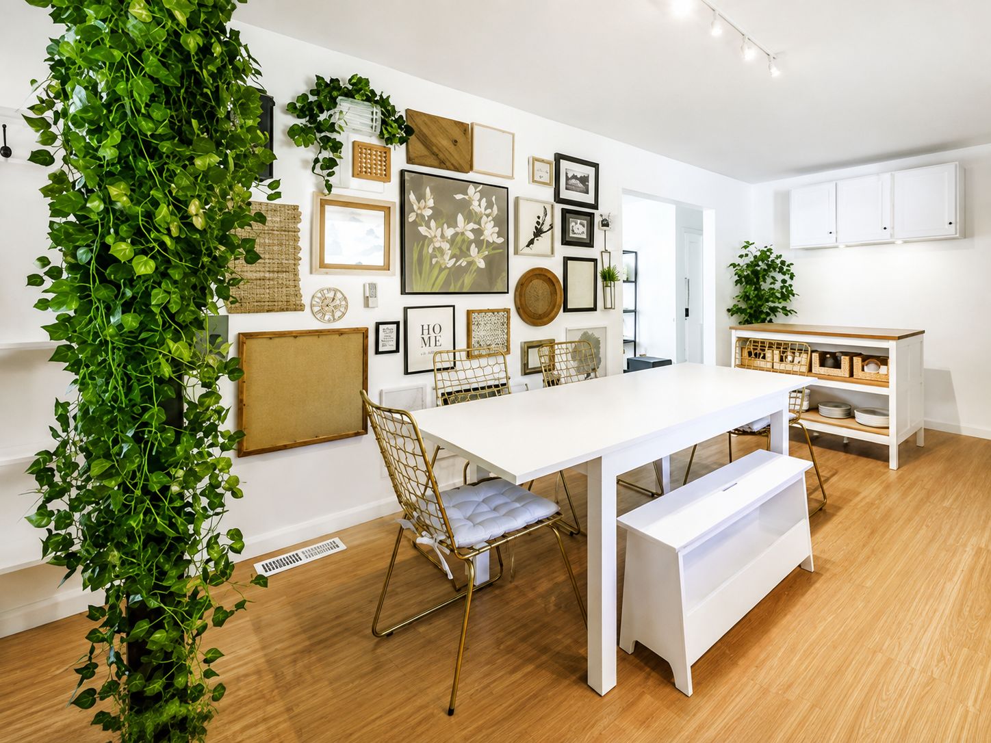 A modern dining area with a white table, gold chairs, and a bench.