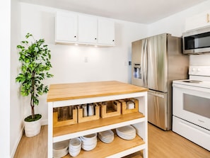 A modern kitchen with white cabinets, a stainless steel refrigerator, and a built-in oven.