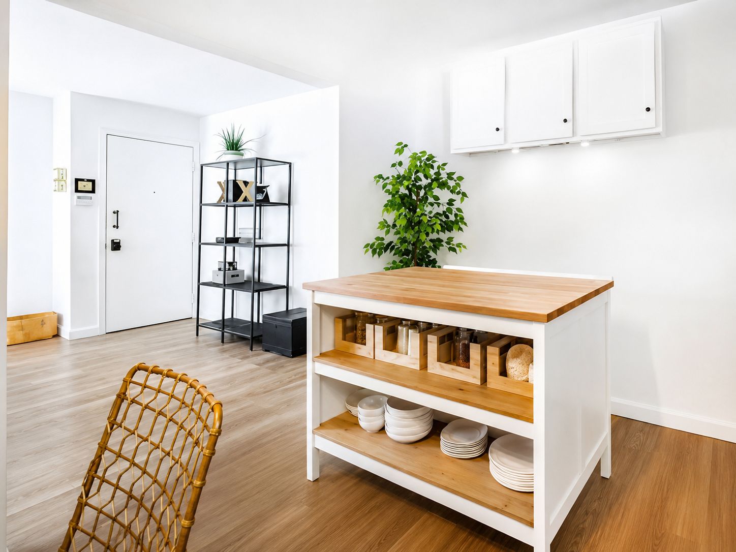 A room with a white cabinet, a plant, and a wicker chair.