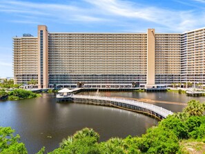 Un grand hôtel à étages, offrant une vue sur le front de mer et relié à un quai par un pont.