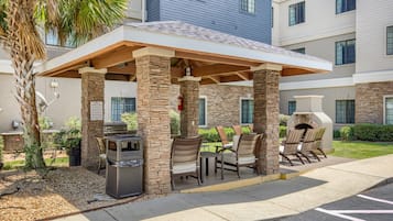 An outdoor patio area with stone pillars, a grill, and seating.
