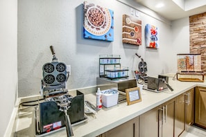 A breakfast bar with waffle makers, a coffee machine, and a variety of food containers.