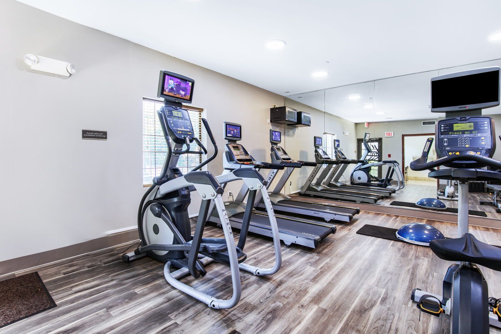 Un gimnasio con cintas de correr, elípticas y bicicletas estáticas.