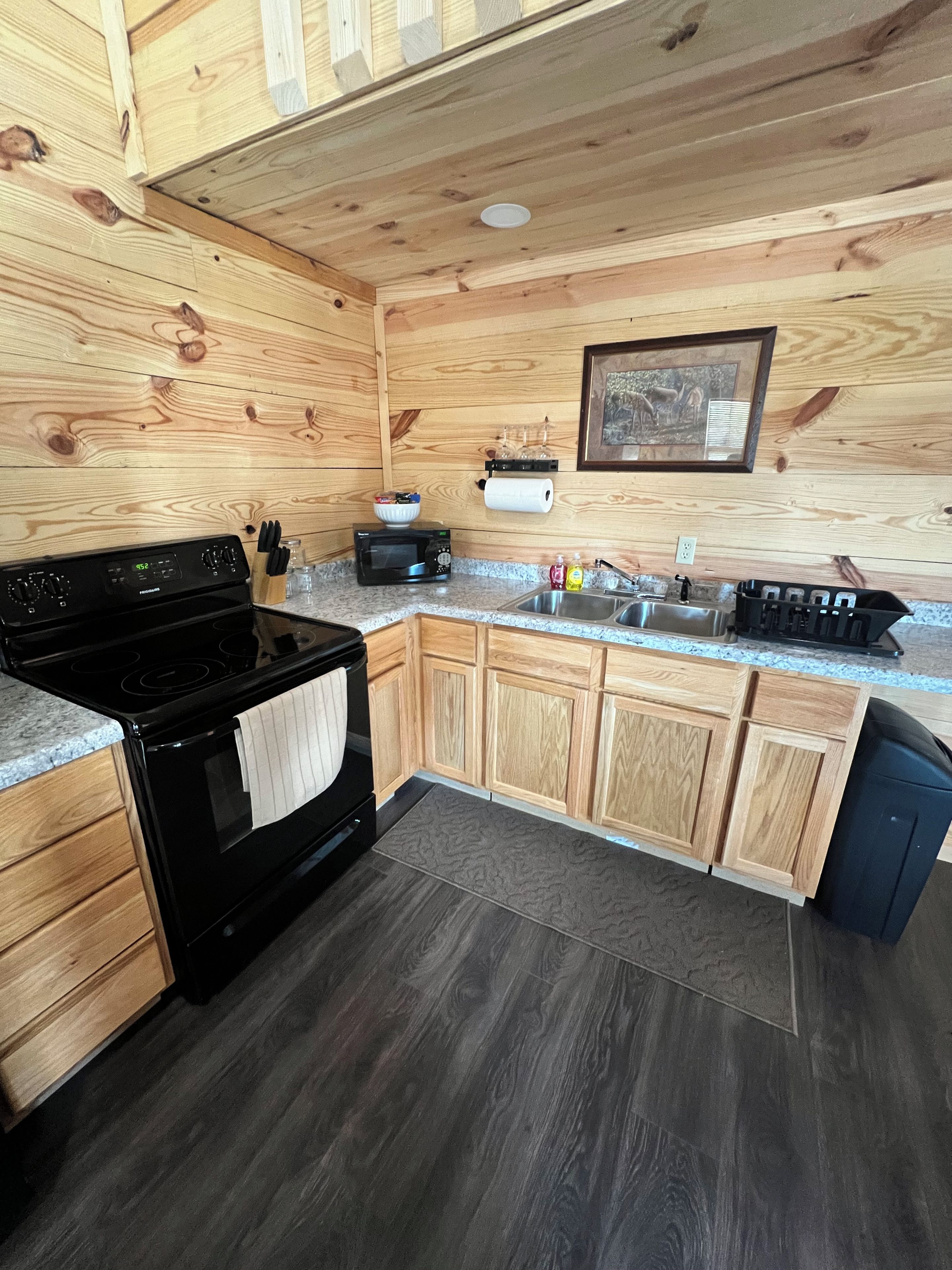 A kitchen with wooden cabinets, a black stove, a microwave, a sink, and a dishwasher.