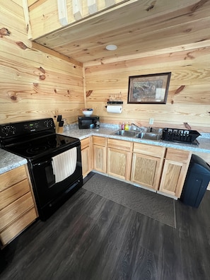 A kitchen with wooden cabinets, a black stove, a microwave, a sink, and a dishwasher.
