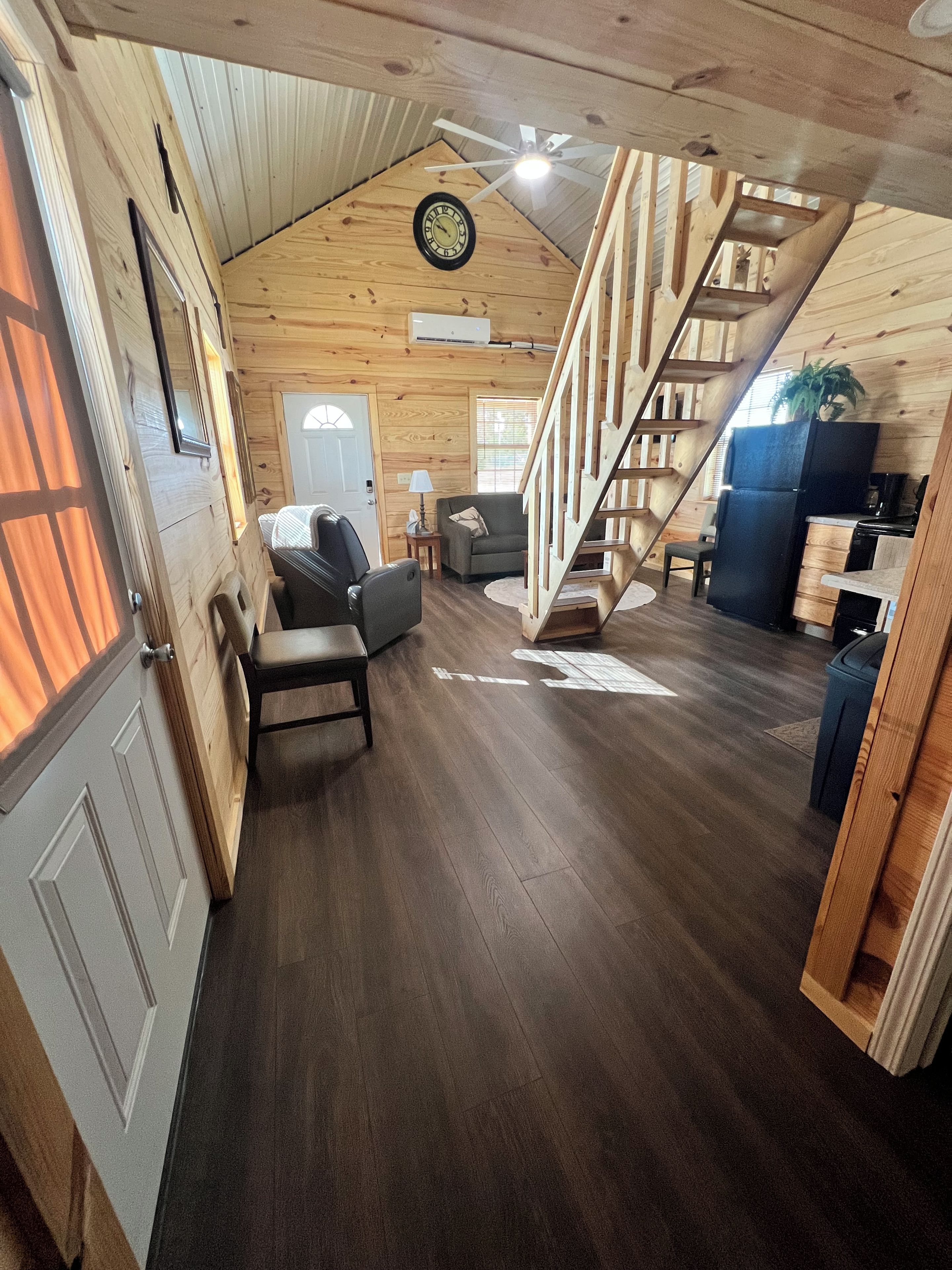 A cozy cabin interior with a wooden staircase, a dining area, and a living room.