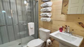 Chuveiro, toalhas de banho, sabonete, papel higiênico