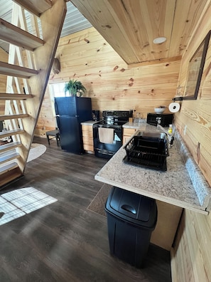 A compact kitchen with a built-in stove, microwave, and a small sink.