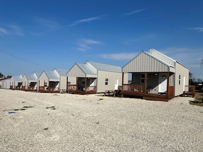 A row of beach cottages with wooden decks and metal roofs.