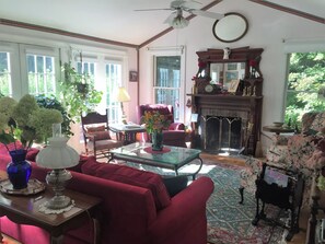 A cozy living room with a fireplace, comfortable seating, and a view of the outdoors.