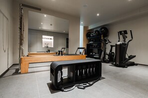 A modern gym with exercise equipment, a wooden bench, and a large mirror. - Villa Brunella by My Villa Collection (Poggibonsi)