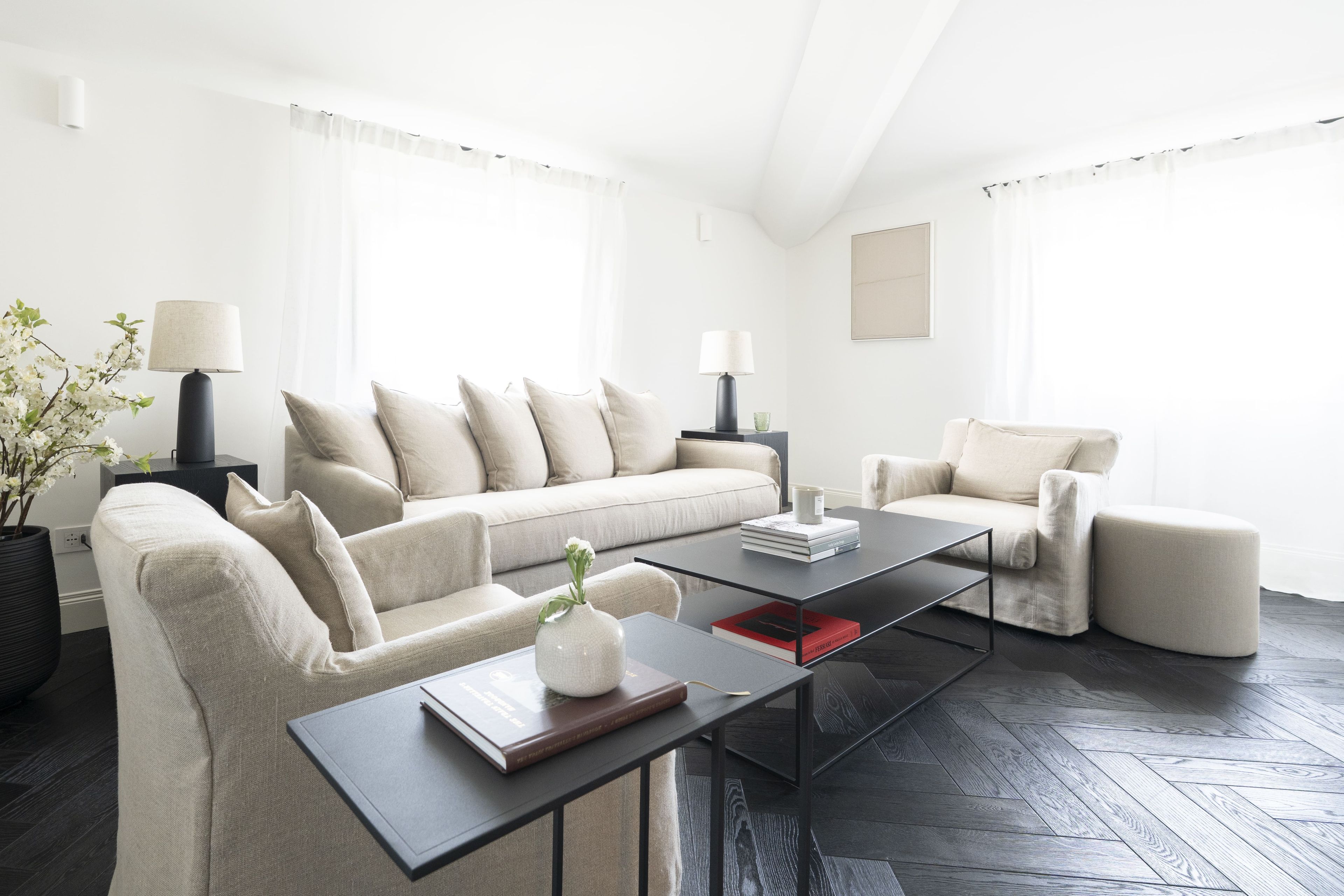 A modern living room with a sofa, armchairs, a coffee table, and a lamp.