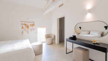 A minimalist bedroom with a bed, a chair, a desk, and a mirror.