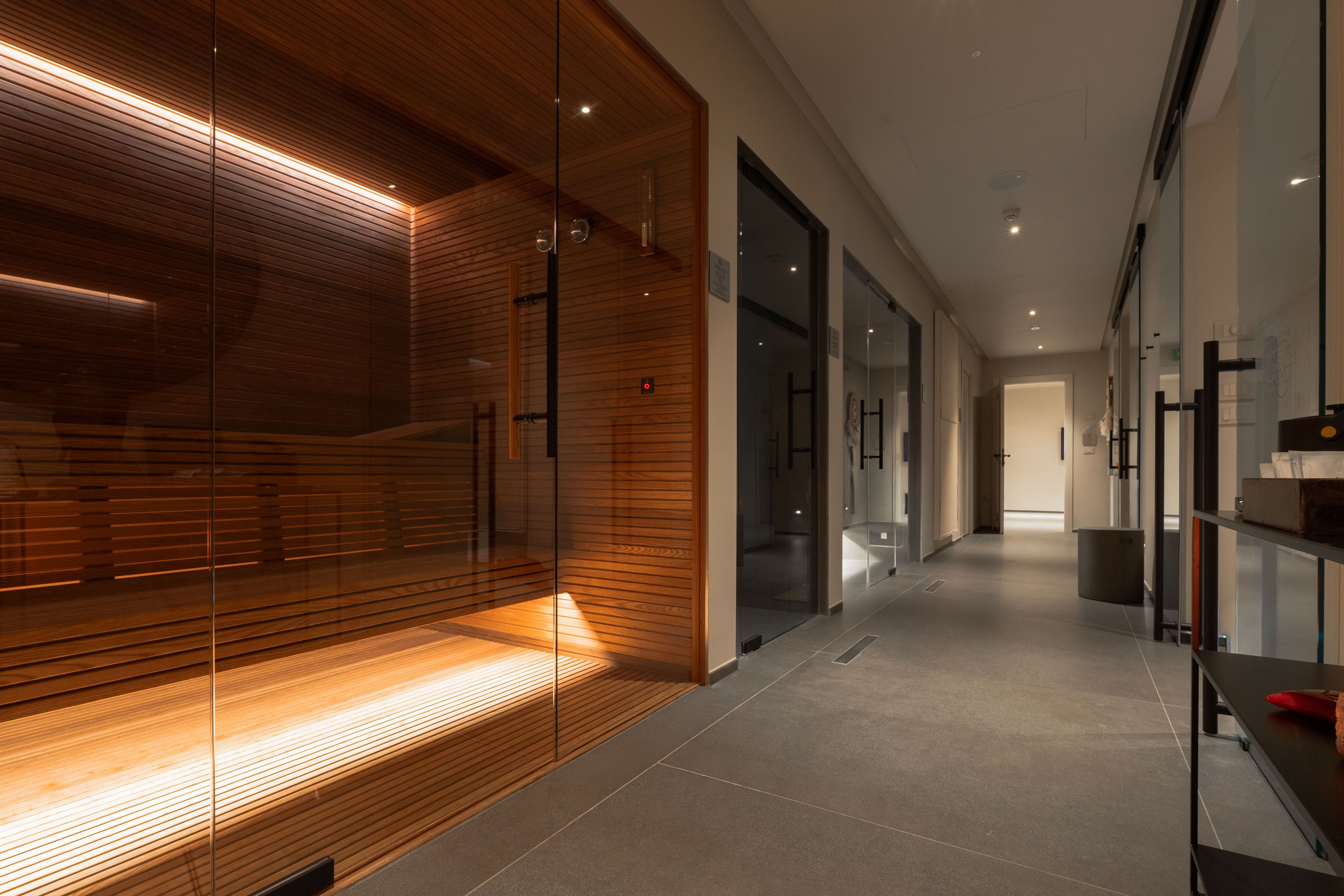 A modern hallway with glass doors, wooden paneling, and a tiled floor.