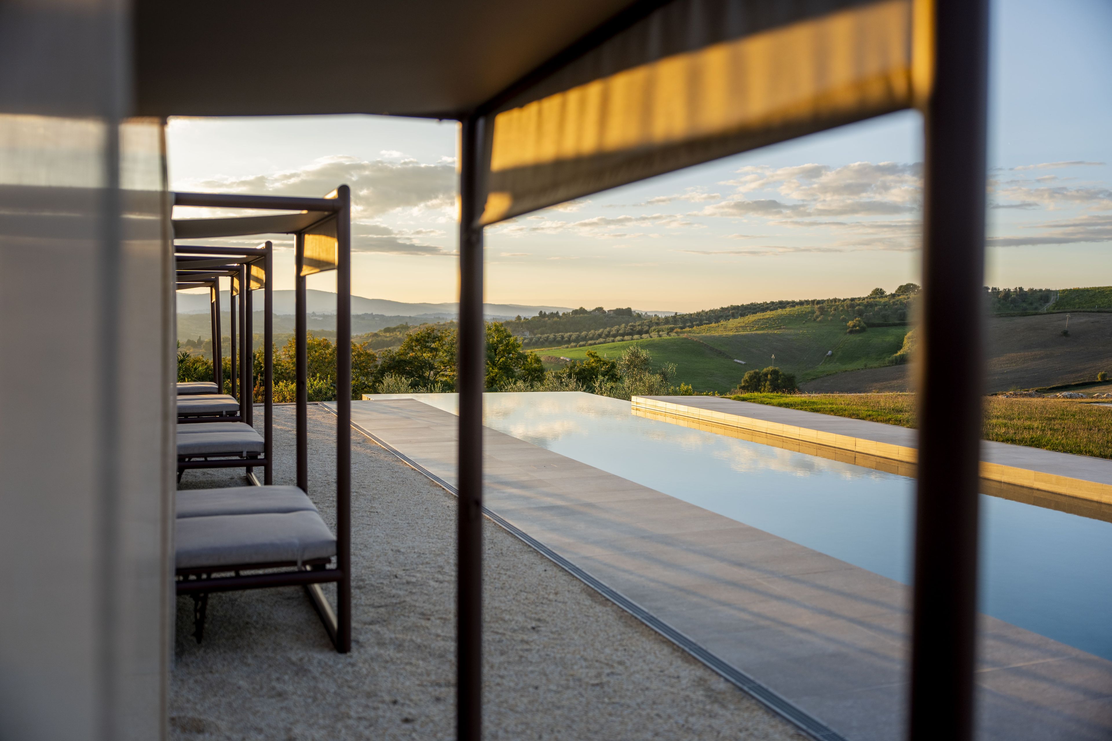A modern outdoor seating area with a view of a landscaped landscape and a pool.