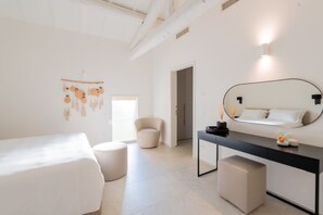 A minimalist bedroom with a bed, a chair, a desk, and a mirror. - Villa Brunella & Cottage by My Villa Collection (Poggibonsi)