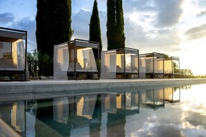 A poolside area with four covered seating areas, each with a cushioned bench and a transparent canopy. - Villa Brunella & Cottage by My Villa Collection (Poggibonsi)