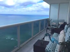 Uma varanda com vista para o mar, um sofá e uma mesa pequena.
