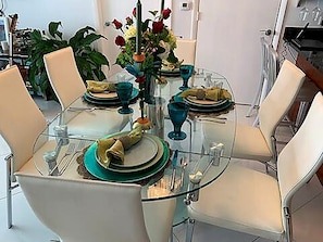 Ein Esstisch mit Stühlen, eine Vase mit Blumen und ein Glastisch.