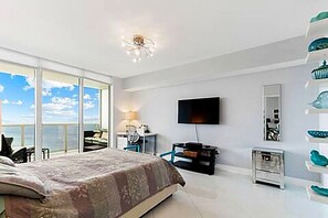 Quarto com cama grande, televisão e vista do céu.
