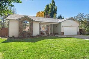 A single-story house with a stone facade, a garage, and a well-maintained lawn. - Fairway & Fly at Sopris - Fishing, Golf, & Hot Tub (Carbondale)