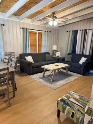 Ein Wohnzimmer mit einer Sofagarnitur, einem Couchtisch und einem Esstisch mit Stühlen.