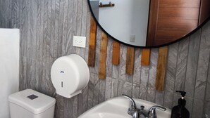 Un baño con un lavabo blanco, un espejo y un mueble de tocador de madera.