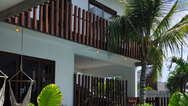 Un edificio moderno con piscina, zona de estar al aire libre y plantas tropicales.