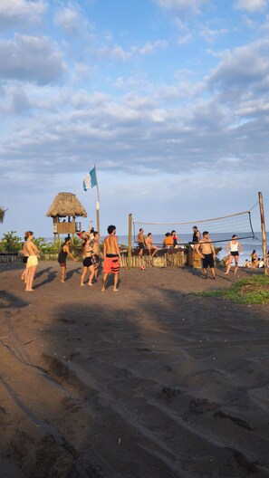 Partido de voleibol de playa con jugadores y espectadores.
