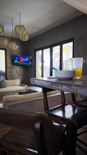 Una sala de estar moderna con un televisor de pantalla plana, una mesa de comedor con sillas y un sofá.