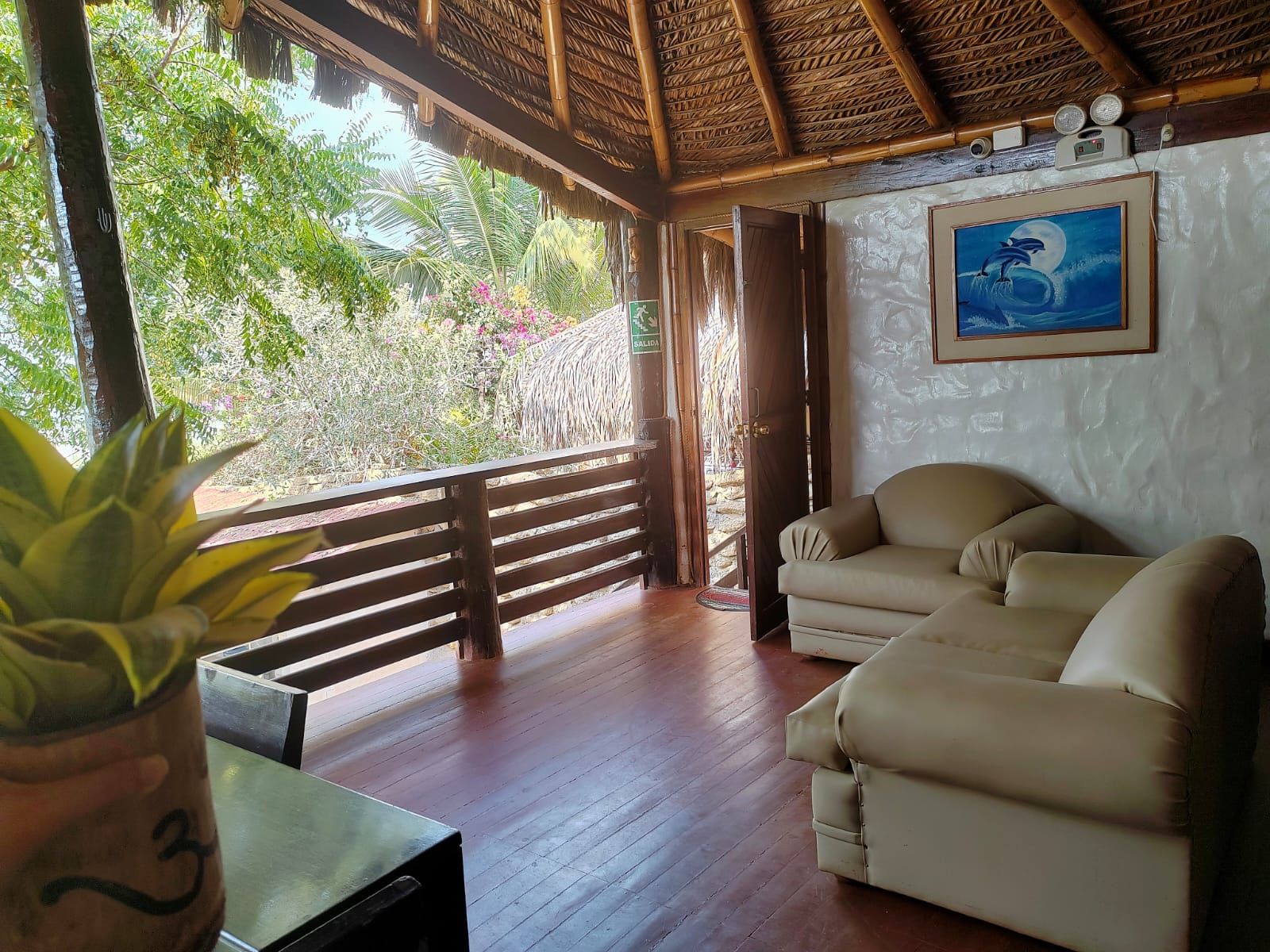 Una habitación con techo de madera, un sofá, una mesa con una planta y un cuadro de delfines.