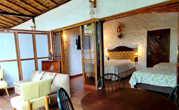 Una habitación con una cama, una mesa y una silla. El techo es de madera y la pared presenta un diseño texturizado.